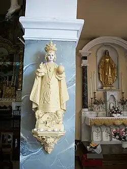 Une statue de l'Enfant Jésus de Prague. À droite la chapelle de la Vierge-Marie.