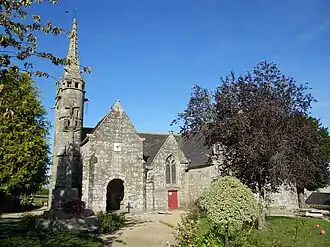 Vue du sud. Le clocher-mur est de profil. Au sud, s'alignent un porche à deux niveaux, le croisillon sud, puis une grande sacristie qui s'étend vers le sud.