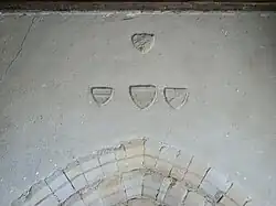 Au-dessus du portail, des basons sculptés en pierre.