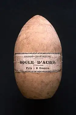 Étui en bois de forme ovoïde, sur lequel est écrit : « Grande chartreuse — Boule d'acier ».