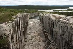 Un corridor creusé dans le rocher mène à un lac. Le corridor ne contient que quelques petites flaques d'eau.