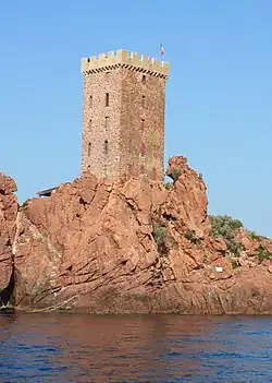 Photographie couleur d'une tour au pied de laquelle un rocher évoque une silhouette de gorille.
