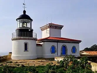 Photographie en couleur d'un phare avec son bâtiment attenant pour les gardiens.