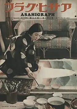 Couverture d'un magazine. La plupart de l'espace est occupé par la photo d'une jeune femme agenouillée en costume traditionnel en train de peindre.