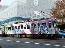 Premier wagon d'un train peint avec un robot Gundam sur la droite et plusieurs personnages sur la gauche.