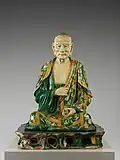 • Arhat(羅漢 Luóhàn).• Époque: Dynastie Liao Xe&nbsp;siècle.• Grès à glaçure tricolore (sancai).• Hauteur: 104,8 cm.• Metropolitan Museum of Art, New-York.