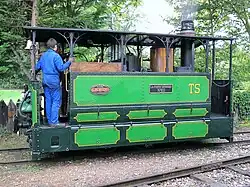 Locomotive à vapeur de tramway équipée d'une toiture et d'un mécanisme masqué par des tôles.
