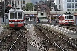 Gare ferroviaire terminus avec plusieurs trains blancs et rouges à l'arrêt.