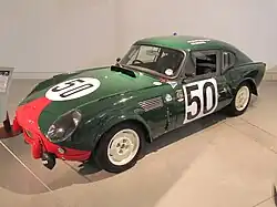 Photo d’une Triumph Spitfire carrossée en coupé, verte avec une bande rouge, portant le numéro de course 50.