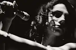 Image en noir et blanc d'une femme tenant un micro dans une de ses mains.