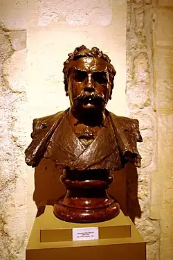 Photo d'un buste d’un homme moustachu à l’air sévère