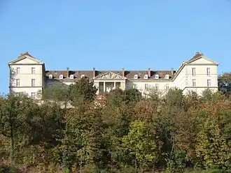 Photographie en couleur d'un bâtiment surplombant des arbres.