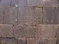 Partie d'un mur de Qasr al Hallabat constitué de blocs de basaltes dont l'un est recouvert d'écritures grecques