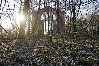 Une borne entre les arbres, la silhouette d'un bâtiment apparaît à l'arrière plan.