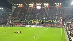 Photo montrant une tribune de stade, barrée d'une grande banderole noire et jaune.