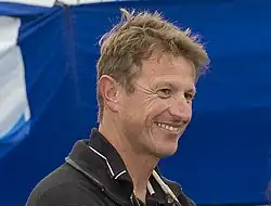 Portrait de trois quarts, souriant.