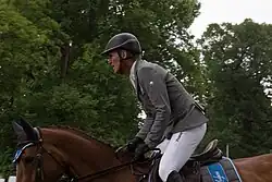 Un homme en équipement de cavalier positionné sur un cheval au repos