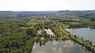 Plan d'eau et zone habitée entre des collines boisées.