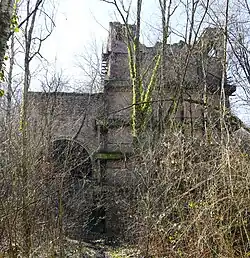 Un grand bâtiment de pierre et de brique entre les arbres.