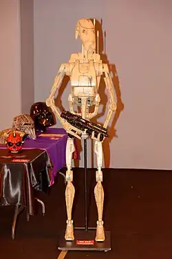 Robot beige, portant une arme.