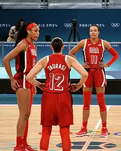 3 joueuses en tenues rouges, debout, placées en demi-cercle