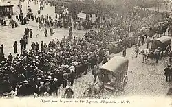 Photo noir et blanc d'une colonne de soldats en marche, entourés par des civils.
