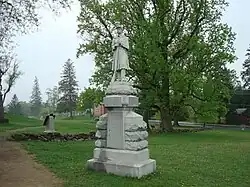 Statue d'un soldat tenant un fusil posé à terre par le canon.