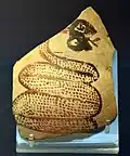 Bris de poterie (tesson) orné d'un serpent qui sort la langue. L'encre vieillissante montre des nuances entre le rouge et noir