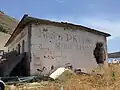 Bâtiment abandonné à Porto Palermo (côté) avec un message socialiste disant "Vive le Parti communiste chinois et le camarade Mao Zedong" (RROFTE PK E KINES DHE SHOKUN MAO CE DUN)