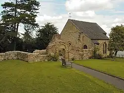 Photo d'un bâtiment aux murs de pierre. Une partie est effondrée, mais un bâtiment bas reste intact.