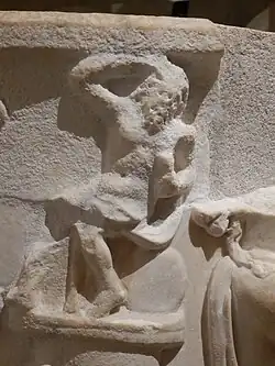 Petit personnage assis en haut de la colonne.