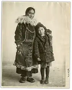photo noir et blanc d'une femme inuit en tenue traditionnelle serrant près d'elle un jeune garçon