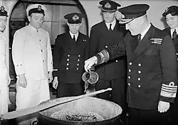 L'amiral Sir Bruce Fraser, commandant en chef de la Home Fleet britannique, verse du rhum dans le mélange pour le Christmas pudding de 1943 à bord du HMS&nbsp;Duke of York (novembre 1943).