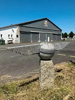 Le hangar de l'aéro-club et le petit monument en granit à l'entrée du site.