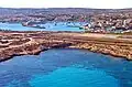 Vue aérienne de l'extrémité occidentale des installations de l'aéroport, avec en arrière-plan le port de la ville de Lampedusa.