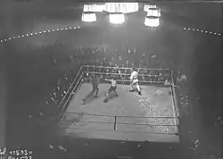 Photographie en noir et blanc prise de haut d'un combat de boxe.