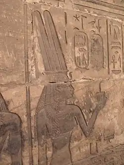 Égyptienne portant la couronne à double plume des reines d'Égypte tendant une offrande à une divinité.
