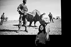 Ami Vitale devant sa photo d'un rhinocéros entouré de gardes forestiers, sur la scène du festival World Press Photo 2018 à Amsterdam