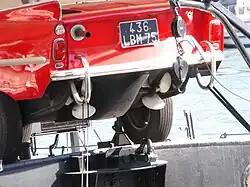 Une Amphicar sur une péniche d'habitation, hélices et tuyau d'échappement.