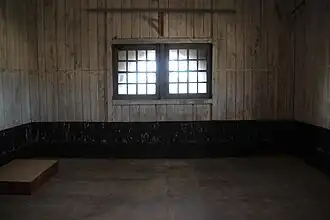 Photographie en couleurs d'une grande pièce éclairée par une fenêtre à barreaux.