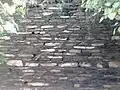 Un ancien mur de schiste monté en « maçonnerie diaprée »: fines lamelles de pierre empilées horizontalement, sur le site