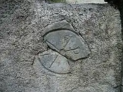 Un chrisme gravée sur une pierre à l'entrée du cimetière et de l'église Saint-Étienne.