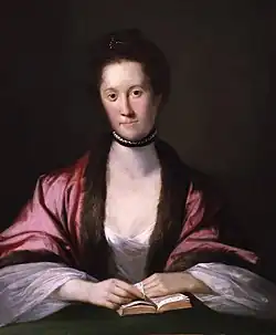 Portrait d'une femme d'âge mûr, lisant un livre, vêtue d'une robe blanche et d'un châle rose-violacé. Posture élégante, collier de perles, expression calme. Style classique du XVIIIe siècle, lumière douce, fond noir.
