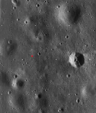 Image haute résolution de Lunar Orbiter 5, recadrée pour montrer le site d'atterrissage d'Apollo 11. Le site d'atterrissage est indiqué par un point rouge. Le cratère proéminent à droite est appelé cratère Ouest et mesure environ 190&nbsp;m de diamètre.