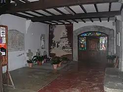 Photographie d’un porche, avec des monuments funéraires.