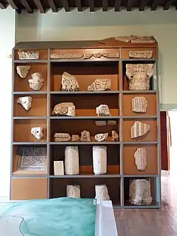 Étagère exposant divers éléments architecturaux en pierre.