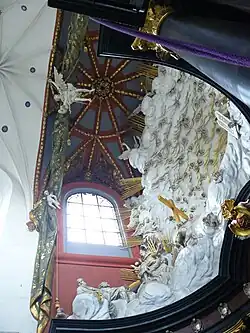 Photographie en contre-plongée d'un décor d'abside baroque et de voûtes à nervures en polychromie.