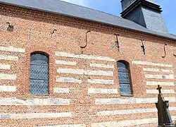 Le mur sud de la nef, dont l'appareil est constitué d'une alternance de pierre calcaire et de brique, porte la date de 1699.