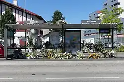 Photographie en couleurs représentant un arrêt de bus, orné de fleurs.