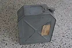 Photographie d'un jerrican en métal gris, censé contenir du pétrole